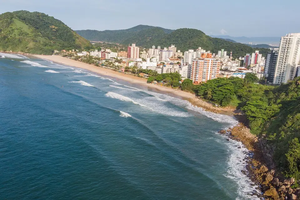 Praia do Tombo, no Guarujá, vista do alto com ondas e prédios ao fundo