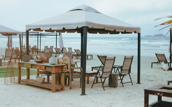 Gazebo com mesa posta na areia da Praia da Enseada, em frente ao Casa Grande Hotel