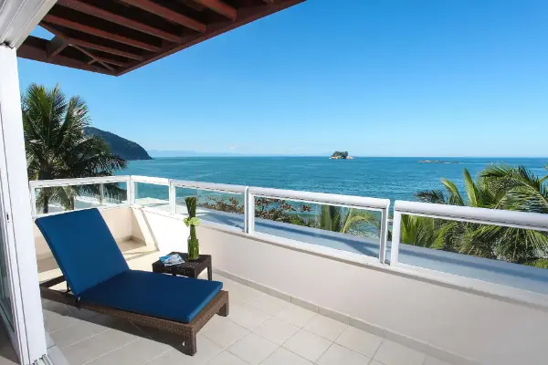 Varanda de suíte do Hotel Jequitimar com espreguiçadeira e vista para o mar